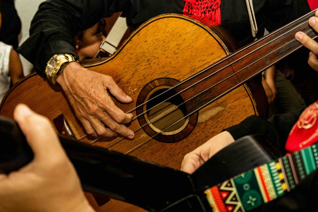 Close-up of a mariachi guitarist’s hands strumming a large acoustic guitar