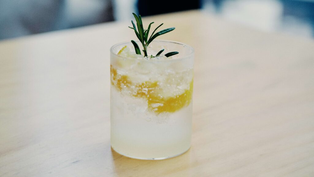 Citrus cocktail layered with lemon slices and herbs in a clear glass